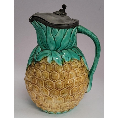 34 - TWO ANTIQUE PEWTER TOPPED JUGS: (i) A lovely antique Majolica style glazed pineapple jug with a hing... 