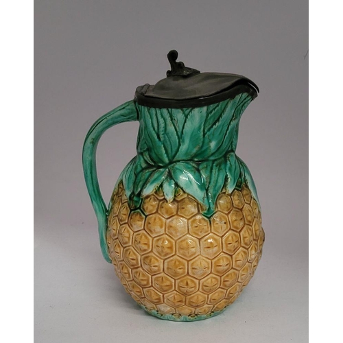 34 - TWO ANTIQUE PEWTER TOPPED JUGS: (i) A lovely antique Majolica style glazed pineapple jug with a hing... 