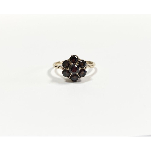 60 - A VINTAGE 9CT YELLOW GOLD SEVEN STONE GARNET CLUSTER RING, with central round cut garnet surrounded ... 