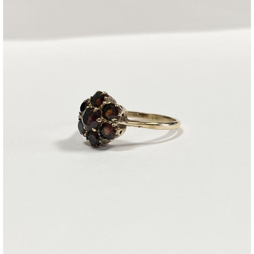 60 - A VINTAGE 9CT YELLOW GOLD SEVEN STONE GARNET CLUSTER RING, with central round cut garnet surrounded ... 