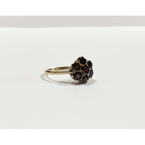 60 - A VINTAGE 9CT YELLOW GOLD SEVEN STONE GARNET CLUSTER RING, with central round cut garnet surrounded ... 