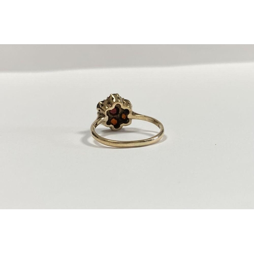 60 - A VINTAGE 9CT YELLOW GOLD SEVEN STONE GARNET CLUSTER RING, with central round cut garnet surrounded ... 