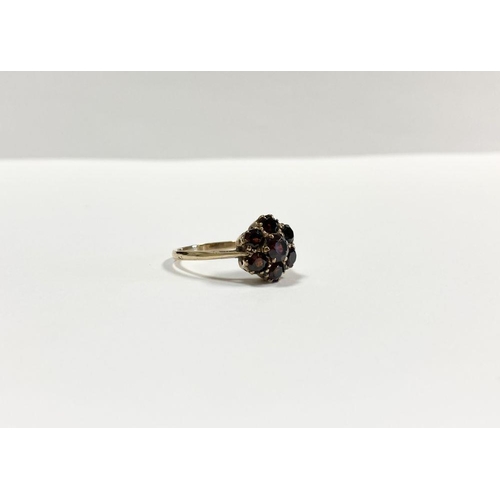 60 - A VINTAGE 9CT YELLOW GOLD SEVEN STONE GARNET CLUSTER RING, with central round cut garnet surrounded ... 