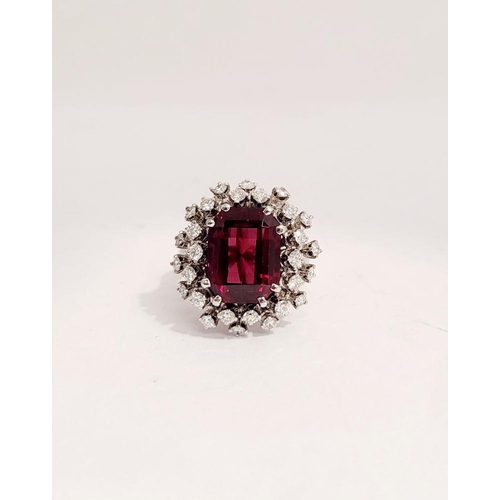 82 - A SUNBURST STYLE COCKTAIL RING: GARNET & DIAMOND BY PIAGET, a large central oval shaped garnet sits ... 