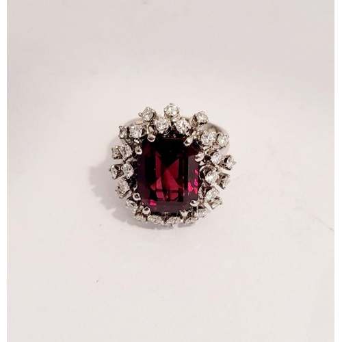 82 - A SUNBURST STYLE COCKTAIL RING: GARNET & DIAMOND BY PIAGET, a large central oval shaped garnet sits ... 