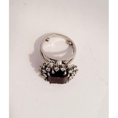 82 - A SUNBURST STYLE COCKTAIL RING: GARNET & DIAMOND BY PIAGET, a large central oval shaped garnet sits ... 