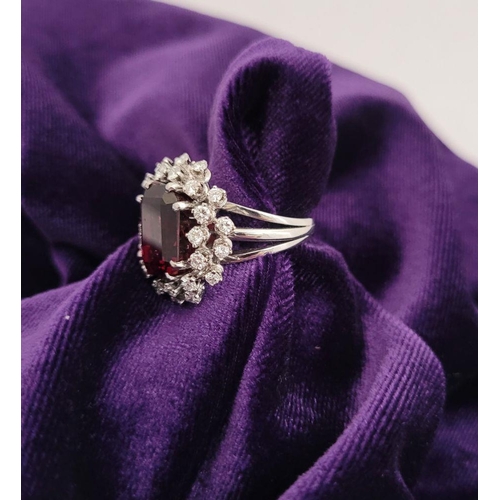 82 - A SUNBURST STYLE COCKTAIL RING: GARNET & DIAMOND BY PIAGET, a large central oval shaped garnet sits ... 