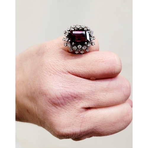 82 - A SUNBURST STYLE COCKTAIL RING: GARNET & DIAMOND BY PIAGET, a large central oval shaped garnet sits ... 