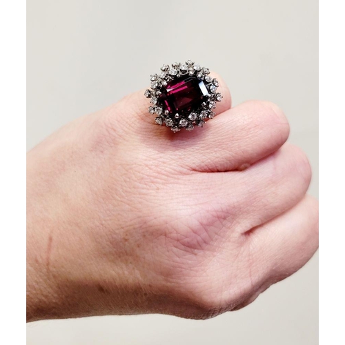 82 - A SUNBURST STYLE COCKTAIL RING: GARNET & DIAMOND BY PIAGET, a large central oval shaped garnet sits ... 