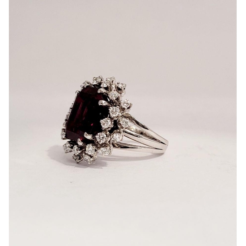 82 - A SUNBURST STYLE COCKTAIL RING: GARNET & DIAMOND BY PIAGET, a large central oval shaped garnet sits ... 