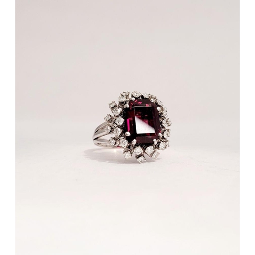 82 - A SUNBURST STYLE COCKTAIL RING: GARNET & DIAMOND BY PIAGET, a large central oval shaped garnet sits ... 