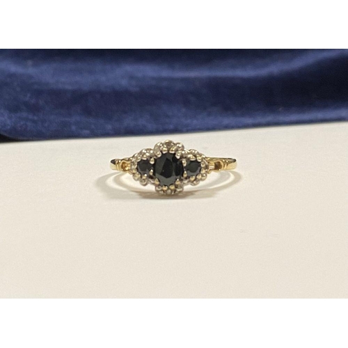 98 - AN ORNATE 9CT GOLD SAPPHIRE AND DIAMOND THREE STONE CLUSTER RING, with central oval cut sapphire fla... 