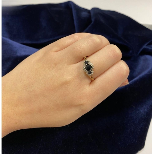 98 - AN ORNATE 9CT GOLD SAPPHIRE AND DIAMOND THREE STONE CLUSTER RING, with central oval cut sapphire fla... 