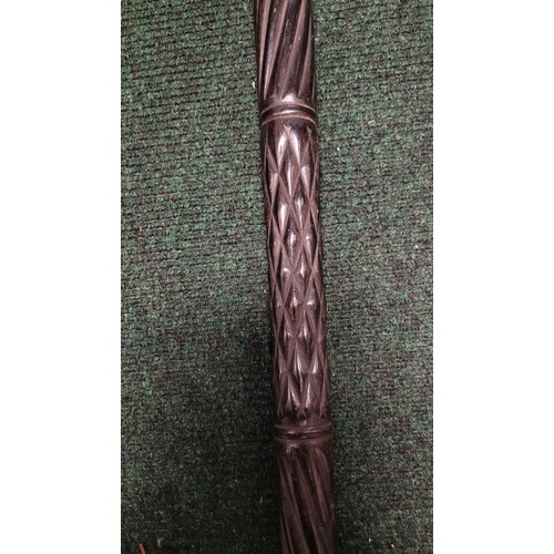 252 - AN ANTIQUE BONE INLAID EBONISED CARVED WALKING STICK, possibly Indian or Sri Lankan, the handle in t... 