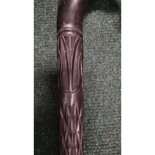 252 - AN ANTIQUE BONE INLAID EBONISED CARVED WALKING STICK, possibly Indian or Sri Lankan, the handle in t... 