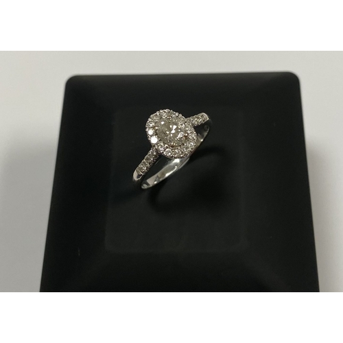 14 - A STUNNING 14CT WHITE GOLD DIAMOND CLUSTER RING, with central oval brilliant cut diamond, weight: .5... 