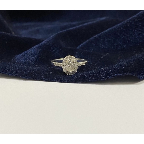 14 - A STUNNING 14CT WHITE GOLD DIAMOND CLUSTER RING, with central oval brilliant cut diamond, weight: .5... 