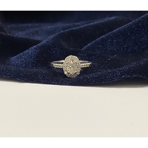 14 - A STUNNING 14CT WHITE GOLD DIAMOND CLUSTER RING, with central oval brilliant cut diamond, weight: .5... 