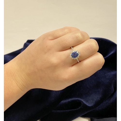 7 - A STRIKING 18CT WHITE GOLD SAPPHIRE & DIAMOND CLUSTER RING, with central vibrant oval cur sapphire i... 