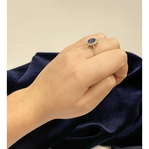 7 - A STRIKING 18CT WHITE GOLD SAPPHIRE & DIAMOND CLUSTER RING, with central vibrant oval cur sapphire i... 