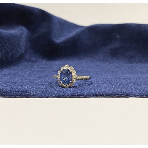 7 - A STRIKING 18CT WHITE GOLD SAPPHIRE & DIAMOND CLUSTER RING, with central vibrant oval cur sapphire i... 