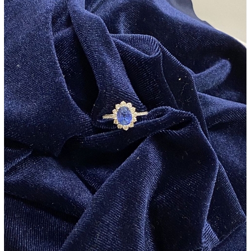 7 - A STRIKING 18CT WHITE GOLD SAPPHIRE & DIAMOND CLUSTER RING, with central vibrant oval cur sapphire i... 