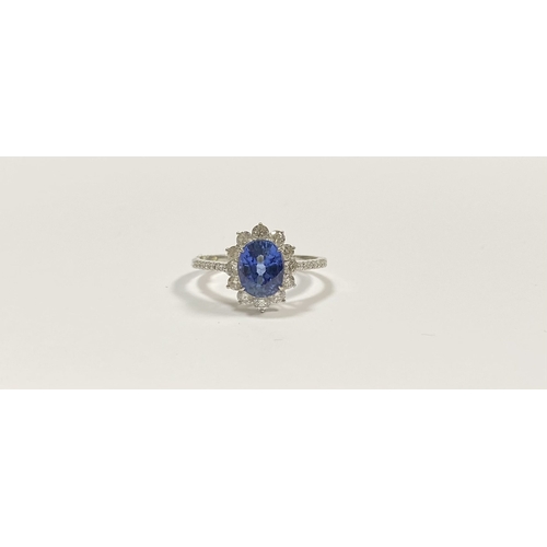 7 - A STRIKING 18CT WHITE GOLD SAPPHIRE & DIAMOND CLUSTER RING, with central vibrant oval cur sapphire i... 