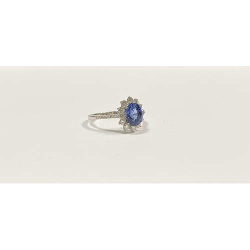 7 - A STRIKING 18CT WHITE GOLD SAPPHIRE & DIAMOND CLUSTER RING, with central vibrant oval cur sapphire i... 