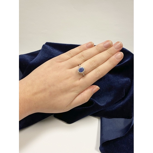 7 - A STRIKING 18CT WHITE GOLD SAPPHIRE & DIAMOND CLUSTER RING, with central vibrant oval cur sapphire i... 