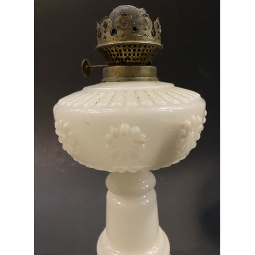 119 - AN ANTIQUE MILK GLASS OIL LAMP, the font with moulded flowers surrounding, on Column base on circula... 