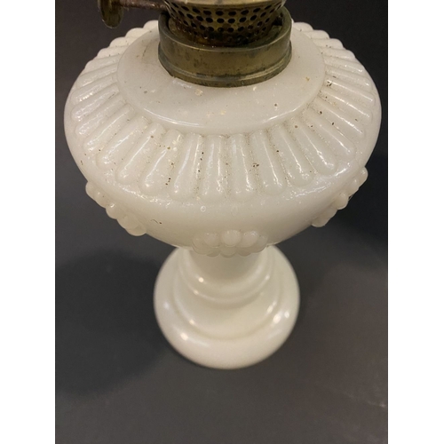 119 - AN ANTIQUE MILK GLASS OIL LAMP, the font with moulded flowers surrounding, on Column base on circula... 