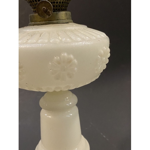 119 - AN ANTIQUE MILK GLASS OIL LAMP, the font with moulded flowers surrounding, on Column base on circula... 