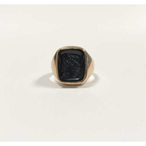 128 - A CARVED BLACK ONYX INTAGLIO SIGNET RING, with central rectangular carved black onyx with rounded co... 