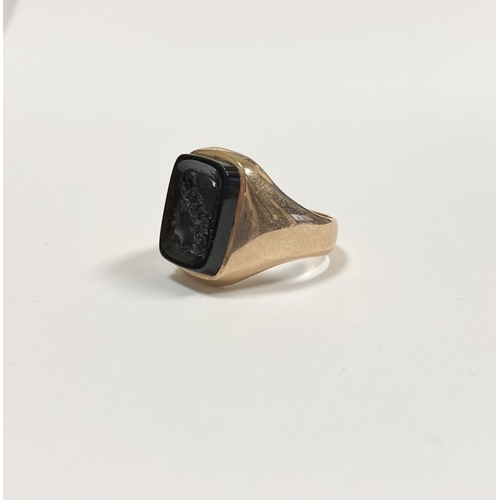 128 - A CARVED BLACK ONYX INTAGLIO SIGNET RING, with central rectangular carved black onyx with rounded co... 