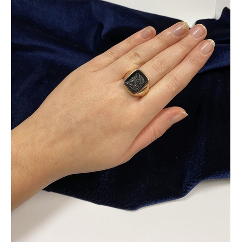 128 - A CARVED BLACK ONYX INTAGLIO SIGNET RING, with central rectangular carved black onyx with rounded co... 