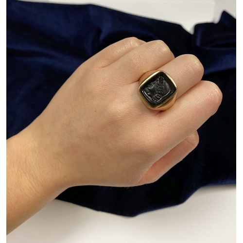 128 - A CARVED BLACK ONYX INTAGLIO SIGNET RING, with central rectangular carved black onyx with rounded co... 