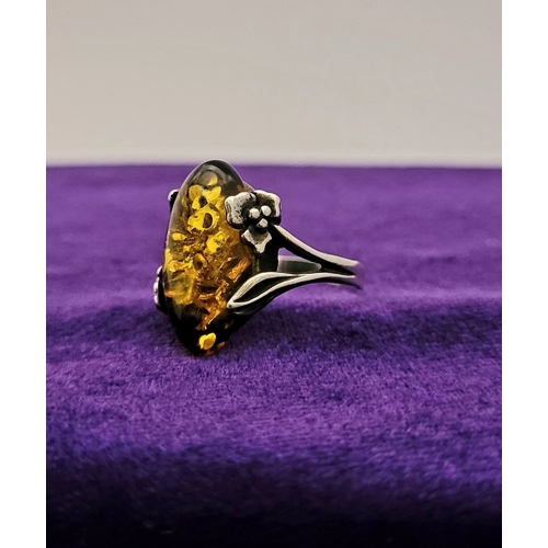 137 - A VINTAGE AMBER RING, with beautiful floral & foliage design to the split shank, unmarked but possib... 