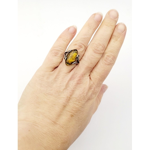 137 - A VINTAGE AMBER RING, with beautiful floral & foliage design to the split shank, unmarked but possib... 