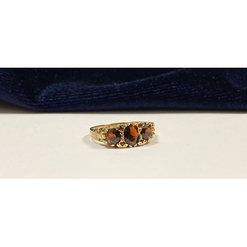 140 - A BEAUTIFUL 9CT YELLOW GOLD THREE STONE GARNET RING, with central oval gut garnet flanked by two rou... 