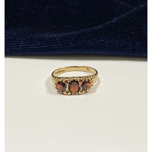 140 - A BEAUTIFUL 9CT YELLOW GOLD THREE STONE GARNET RING, with central oval gut garnet flanked by two rou... 