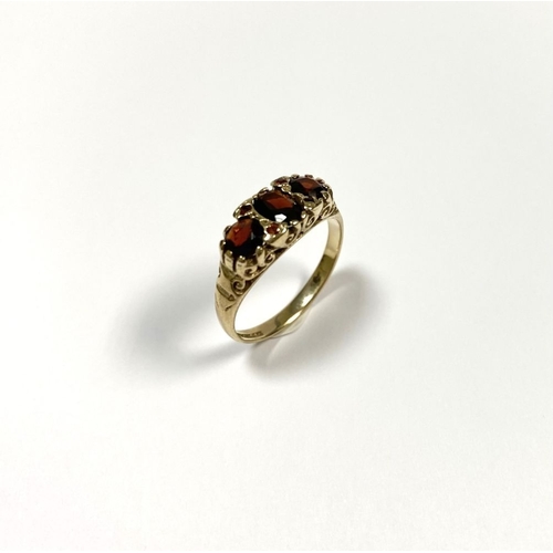 140 - A BEAUTIFUL 9CT YELLOW GOLD THREE STONE GARNET RING, with central oval gut garnet flanked by two rou... 