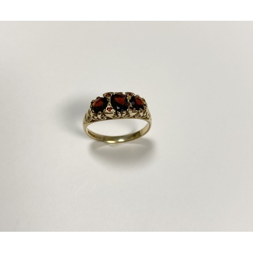 140 - A BEAUTIFUL 9CT YELLOW GOLD THREE STONE GARNET RING, with central oval gut garnet flanked by two rou... 