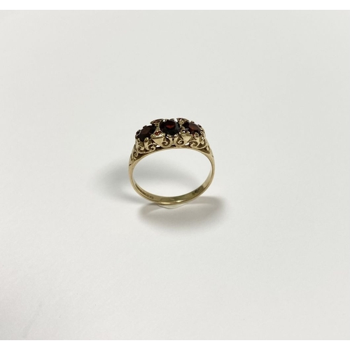 140 - A BEAUTIFUL 9CT YELLOW GOLD THREE STONE GARNET RING, with central oval gut garnet flanked by two rou... 