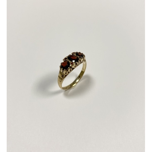 140 - A BEAUTIFUL 9CT YELLOW GOLD THREE STONE GARNET RING, with central oval gut garnet flanked by two rou... 