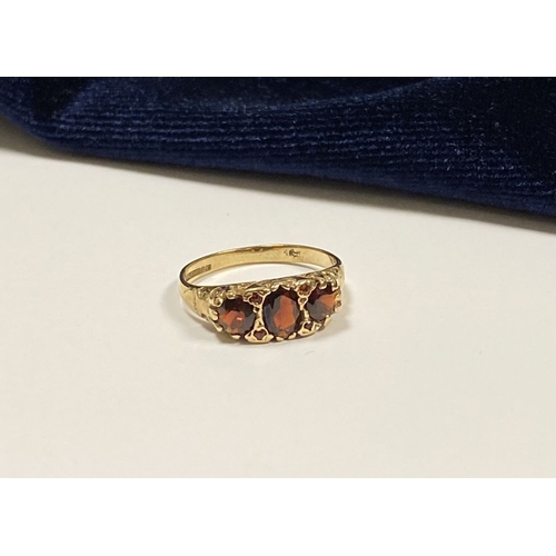 140 - A BEAUTIFUL 9CT YELLOW GOLD THREE STONE GARNET RING, with central oval gut garnet flanked by two rou... 