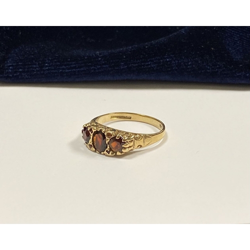 140 - A BEAUTIFUL 9CT YELLOW GOLD THREE STONE GARNET RING, with central oval gut garnet flanked by two rou... 