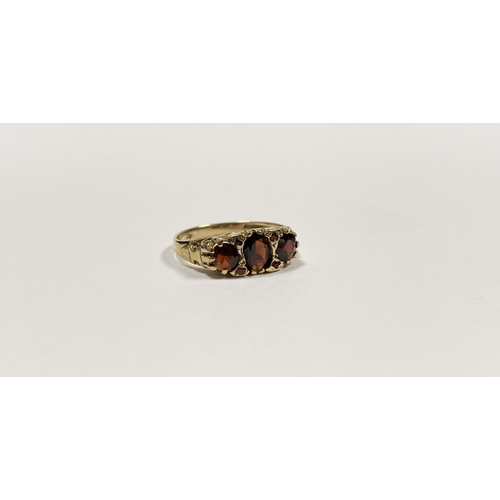 140 - A BEAUTIFUL 9CT YELLOW GOLD THREE STONE GARNET RING, with central oval gut garnet flanked by two rou... 