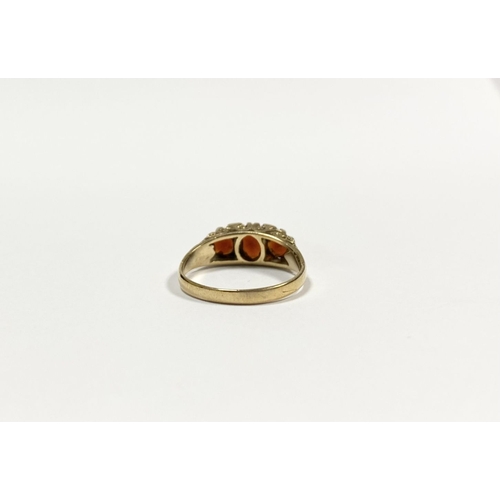 140 - A BEAUTIFUL 9CT YELLOW GOLD THREE STONE GARNET RING, with central oval gut garnet flanked by two rou... 