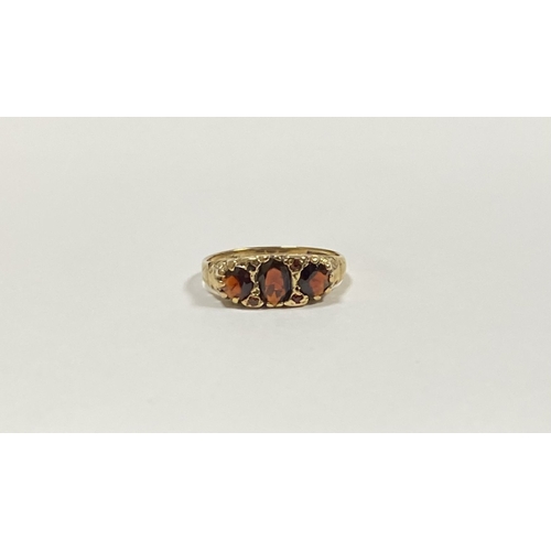 140 - A BEAUTIFUL 9CT YELLOW GOLD THREE STONE GARNET RING, with central oval gut garnet flanked by two rou... 