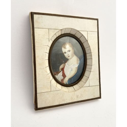 15 - A 19TH CENTURY BONE FRAMED OVAL MINIATURE PORTRAIT, depicting and infant, semi-reclined on blue cush... 